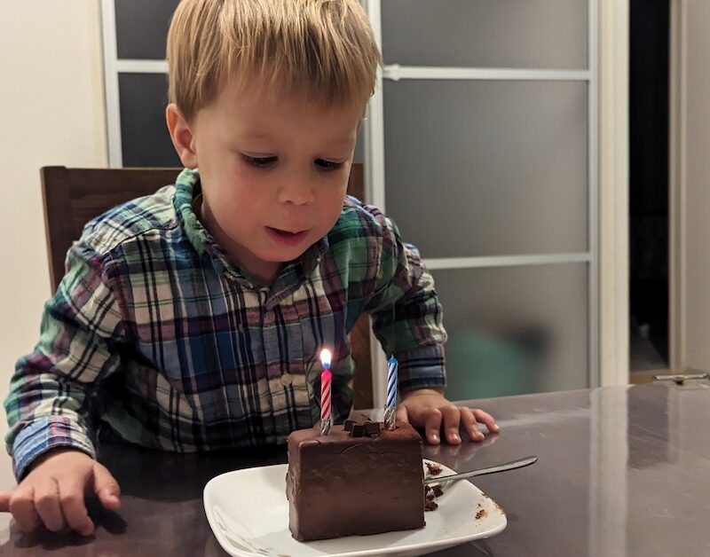 Picture of Ezra blowing out candles on a piece of choloclate cake